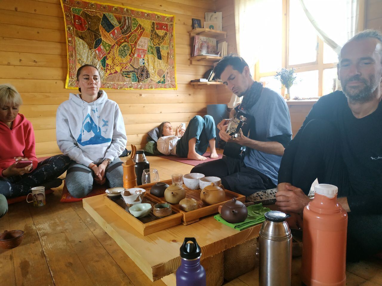 Gruppe sitzt beim Tee im Holzhaus